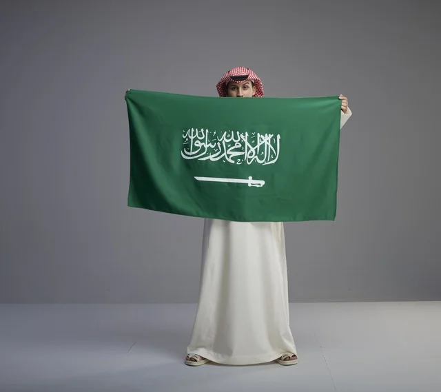 رجل سعودي يحمل العلم الوطني للمملكة العربية السعودية