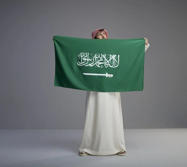 رجل سعودي يحمل العلم الوطني السعودي في الاستوديو