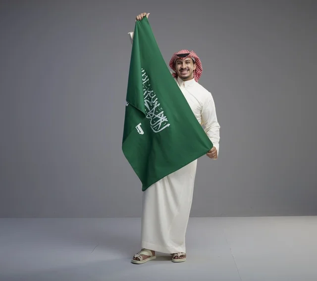 رجل سعودي يحمل العلم الوطني السعودي في استوديو
