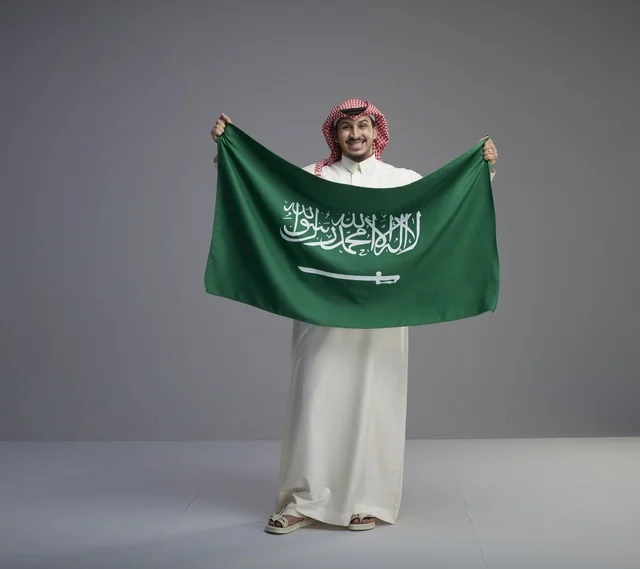 رجل سعودي يحمل العلم الوطني السعودي في الاستوديو