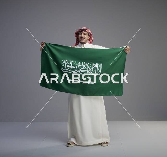 رجل سعودي يحمل العلم الوطني في الاستوديو