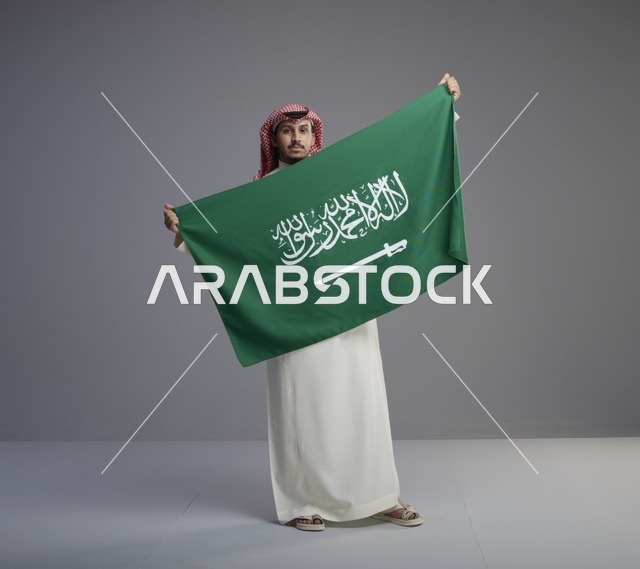 رجل سعودي يحمل العلم الوطني بالزي التقليدي
