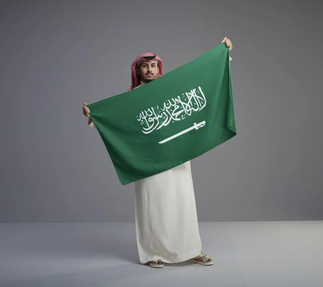 Saudi Man Holding National Flag in Traditional Dress Saudi Man Holding National Flag in Traditional Dress