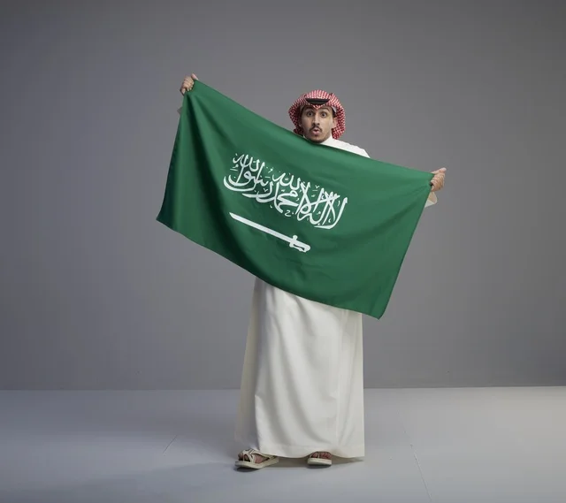 Saudi Man Holding Saudi Arabian National Flag in Studio