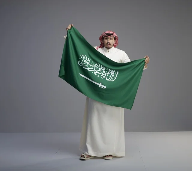 رجل سعودي يحمل العلم الوطني في الاستوديو