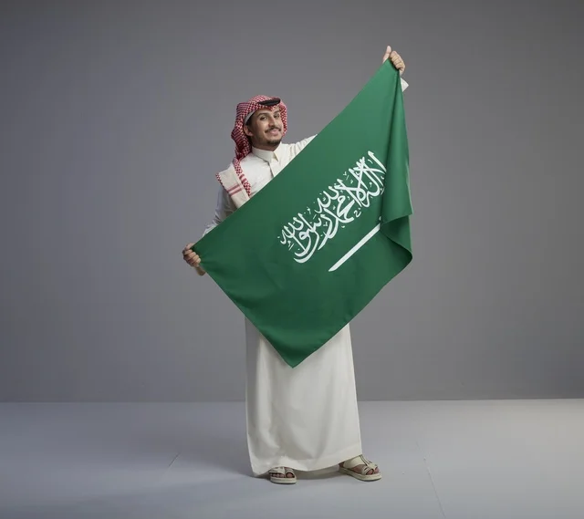 رجل سعودي يحمل العلم الوطني السعودي في الاستوديو