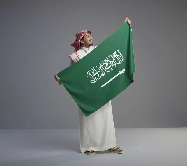 رجل سعودي يحمل العلم الوطني السعودي في الاستوديو
