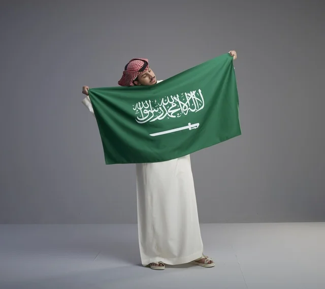 رجل سعودي يحمل العلم السعودي في الاستوديو