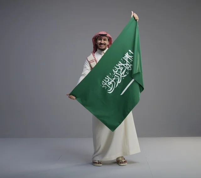 رجل سعودي يحمل علم المملكة العربية السعودية