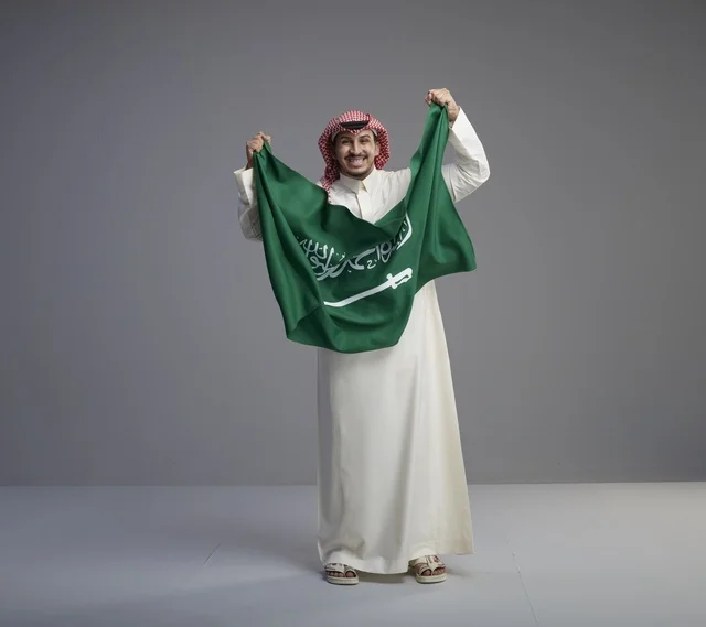 Saudi Man Holding KSA National Flag in Studio Portrait