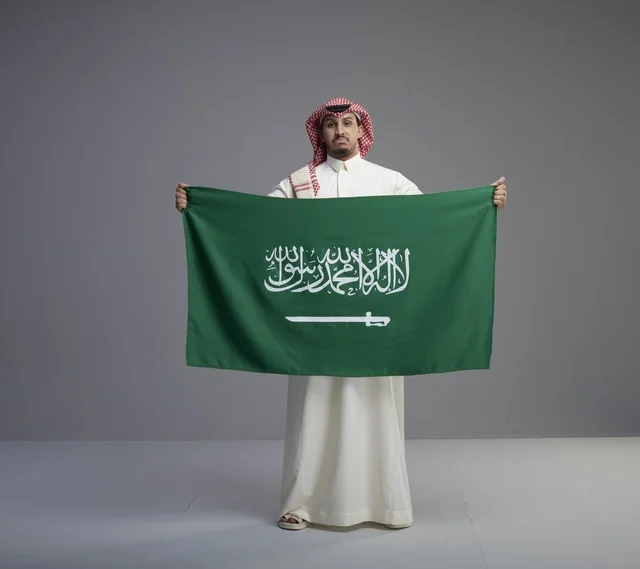 Saudi Man Holding Saudi Arabian National Flag in Studio