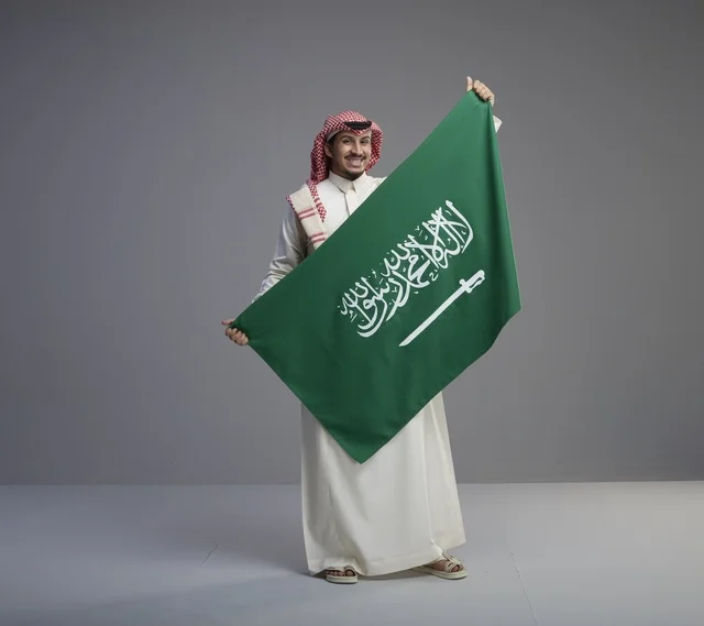 رجل سعودي يحمل العلم الوطني السعودي في الاستوديو