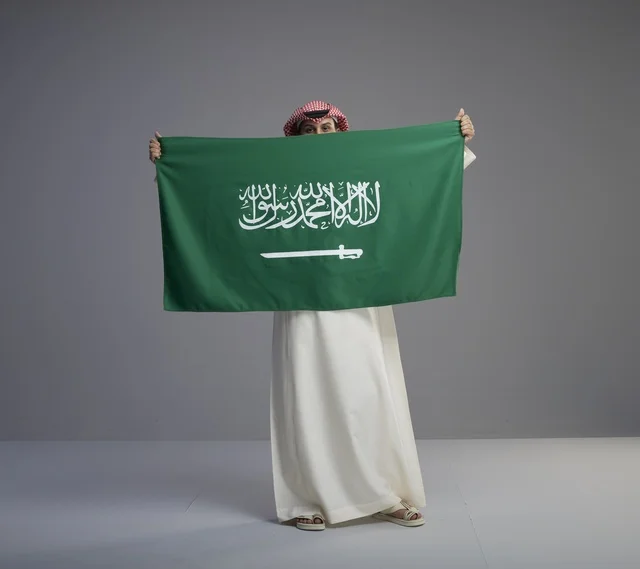رجل سعودي يحمل العلم الوطني السعودي في استوديو
