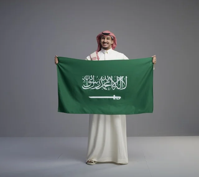 Saudi Man Holding Saudi Arabian National Flag in Studio