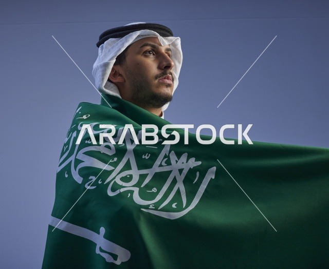 شاب سعودي يلتف بالعلم الوطني للمملكة العربية السعودية