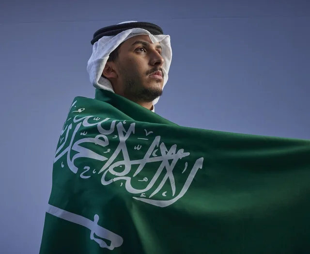 شاب سعودي يلتف بالعلم الوطني للمملكة العربية السعودية
