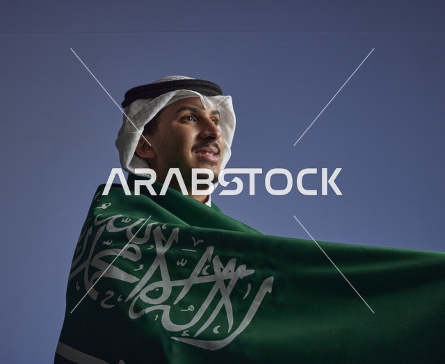 شاب سعودي يلتف بالعلم السعودي بمناسبة اليوم الوطني