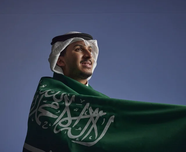 شاب سعودي يلتف بالعلم السعودي بمناسبة اليوم الوطني