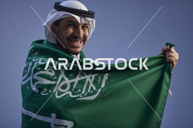 شاب سعودي يلتف بالعلم السعودي في اليوم الوطني