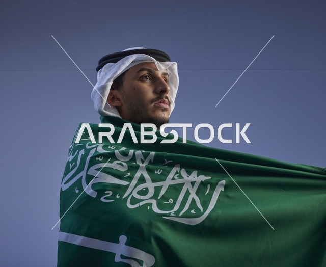 شاب سعودي يلتف بالعلم السعودي تحت السماء