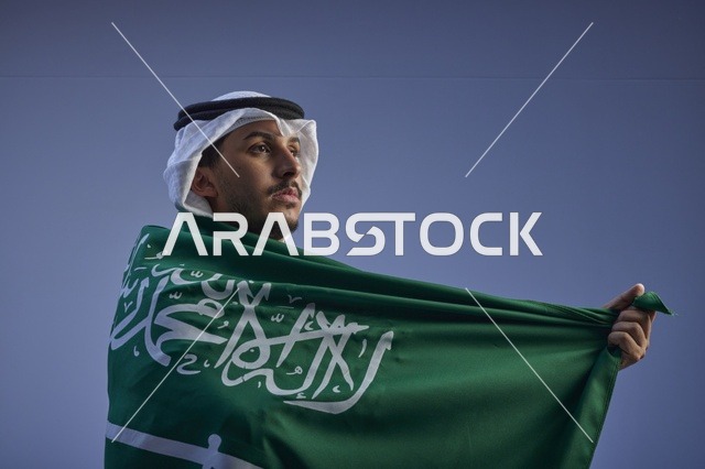 شاب سعودي يلتف بالعلم السعودي في احتفالات اليوم الوطني