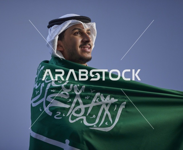 شاب سعودي يرتدي العلم الوطني بالزي التقليدي