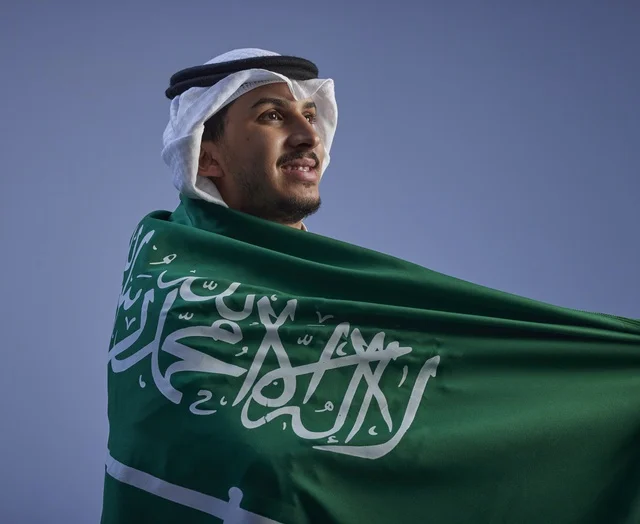 شاب سعودي يرتدي العلم الوطني بالزي التقليدي