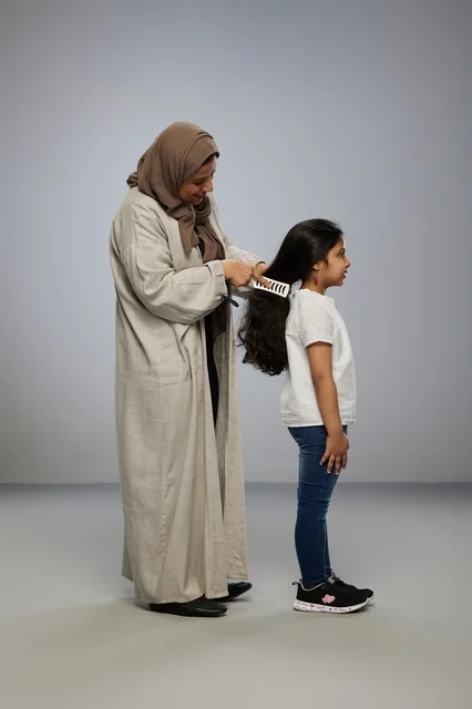 Saudi Mother Brushing Daughter Hair in Studio Background