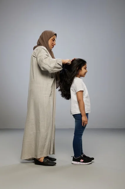 Saudi Mother Combing Her Daughter's Hair in Studio Setting