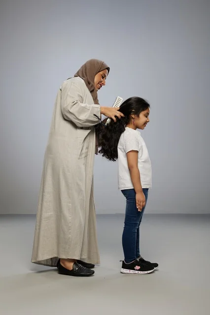 Saudi Mother Brushing Daughter Hair in Studio Saudi Mother Brushing Daughter Hair in Studio