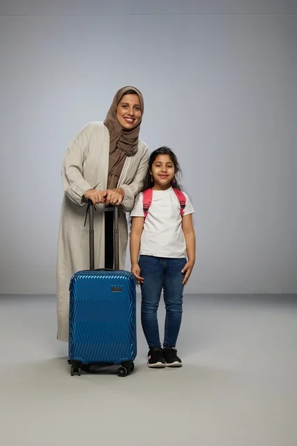 أم سعودية وابنتها مع حقيبة سفر زرقاء