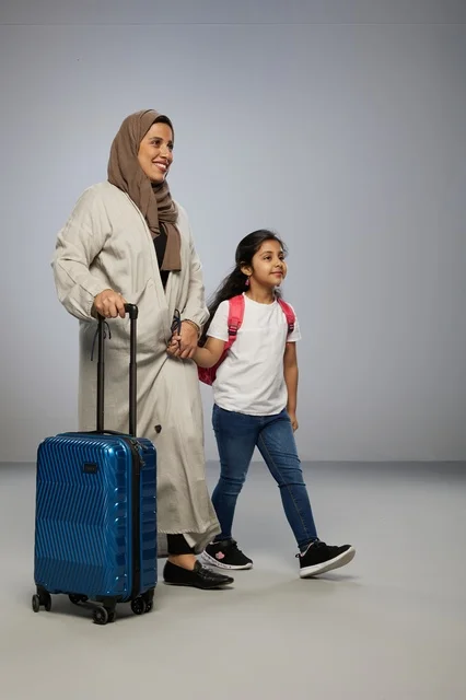 Saudi Mother and Daughter Traveling with Blue Suitcase