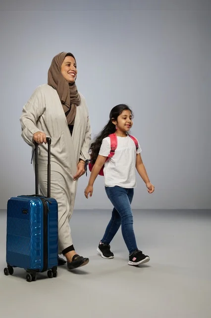 Saudi Mother and Daughter Walking with Suitcase in Studio