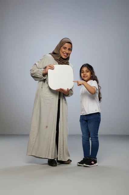 أم وابنة سعوديتان تحملان لوحة بيضاء فارغة في استوديو