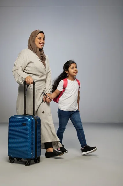 Saudi Mother and Daughter Traveling with Blue Suitcase