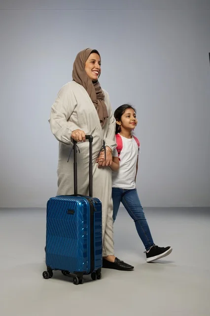 Saudi Mother and Daughter Walking with Blue Suitcase