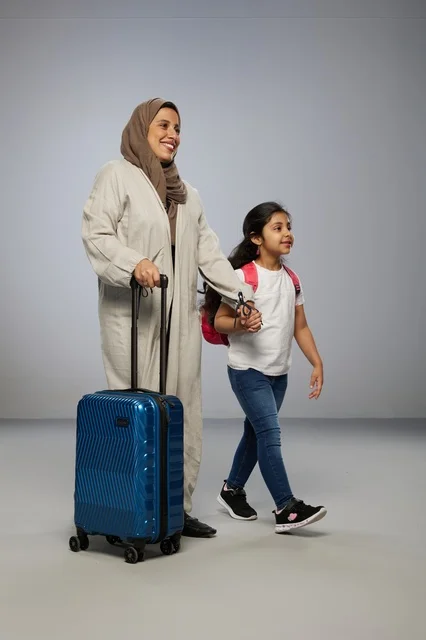 أم وابنتها سعوديتان تمشيان مع حقيبة سفر