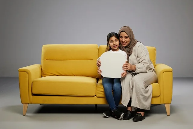 أم سعودية وابنتها تحملان لوحة إعلانية فارغة