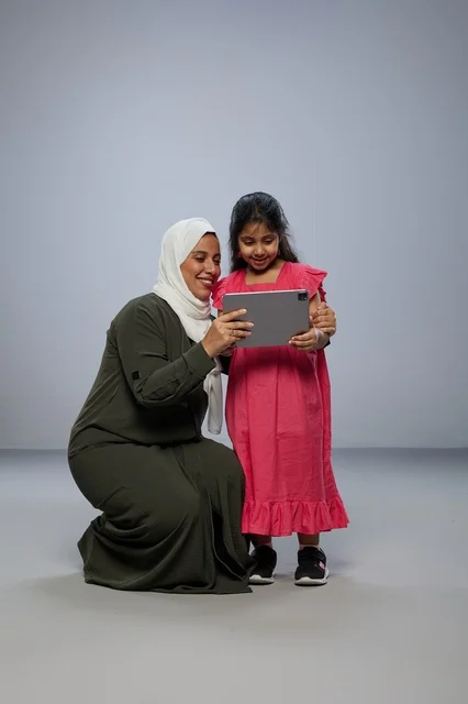 أم وابنتها السعوديتان تستخدمان جهازاً لوحياً في الاستوديو