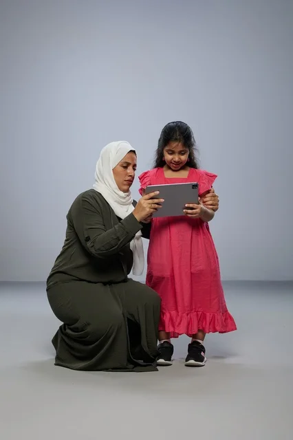 أم سعودية وابنتها تستخدمان جهازاً لوحياً في الاستوديو