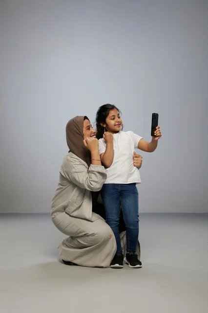 أم سعودية وطفلتها تلتقطان صورة سيلفي بالهاتف في استوديو
