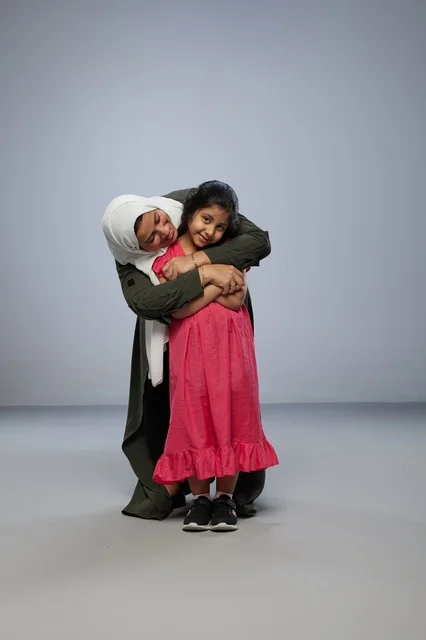 Saudi Mother and Daughter Hugging on Grey Background