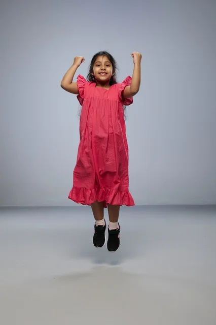 Saudi Girl Jumping in Pink Dress Gray Background