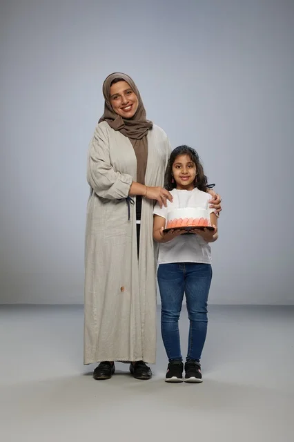 أم سعودية مع ابنتها تحمل كعكة في الاستوديو