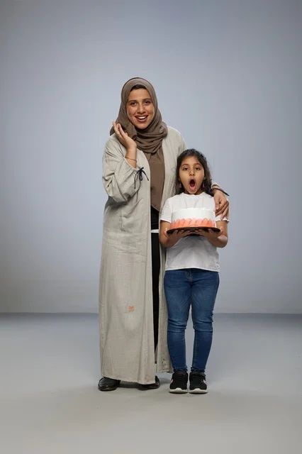 أم سعودية وابنتها مع كعكة عيد ميلاد في الاستوديو