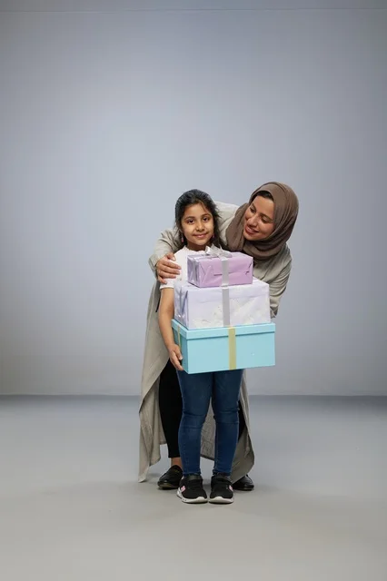 أم عربية وابنتها مع صناديق هدايا في خلفية استوديو