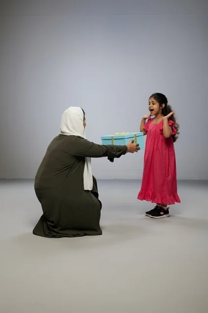Arab Mother Giving Gift to Young Daughter in Studio