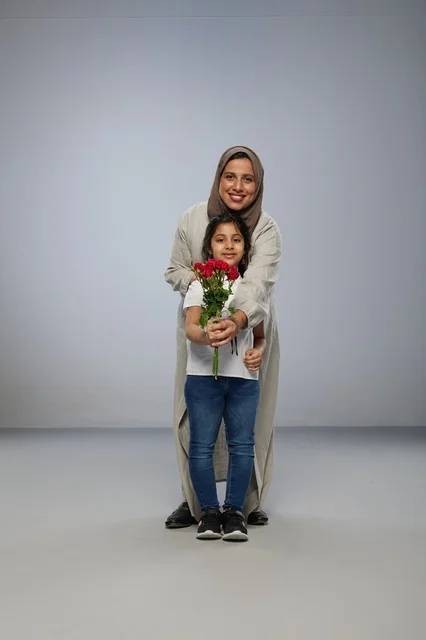 أم وطفلة سعودية مع باقة ورد حمراء في استوديو تصوير