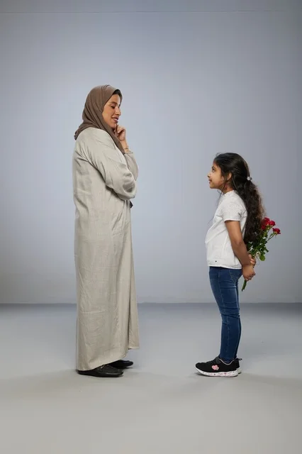 طفلة تخفي الورود الحمراء خلف ظهرها لوالدتها