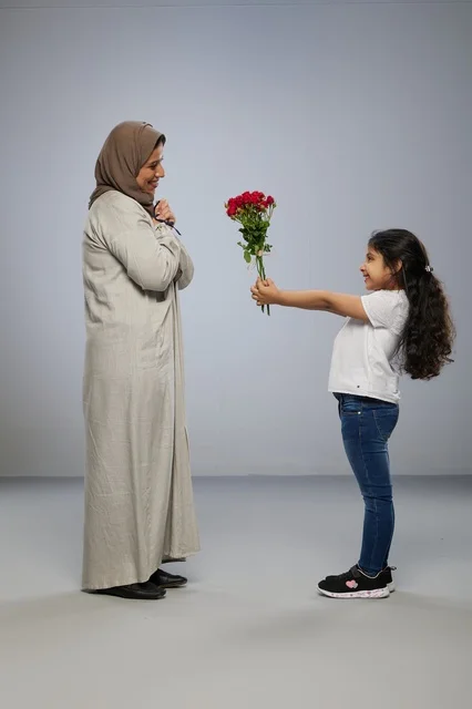 طفلة عربية تقدم زهور حمراء لوالدتها في استوديو